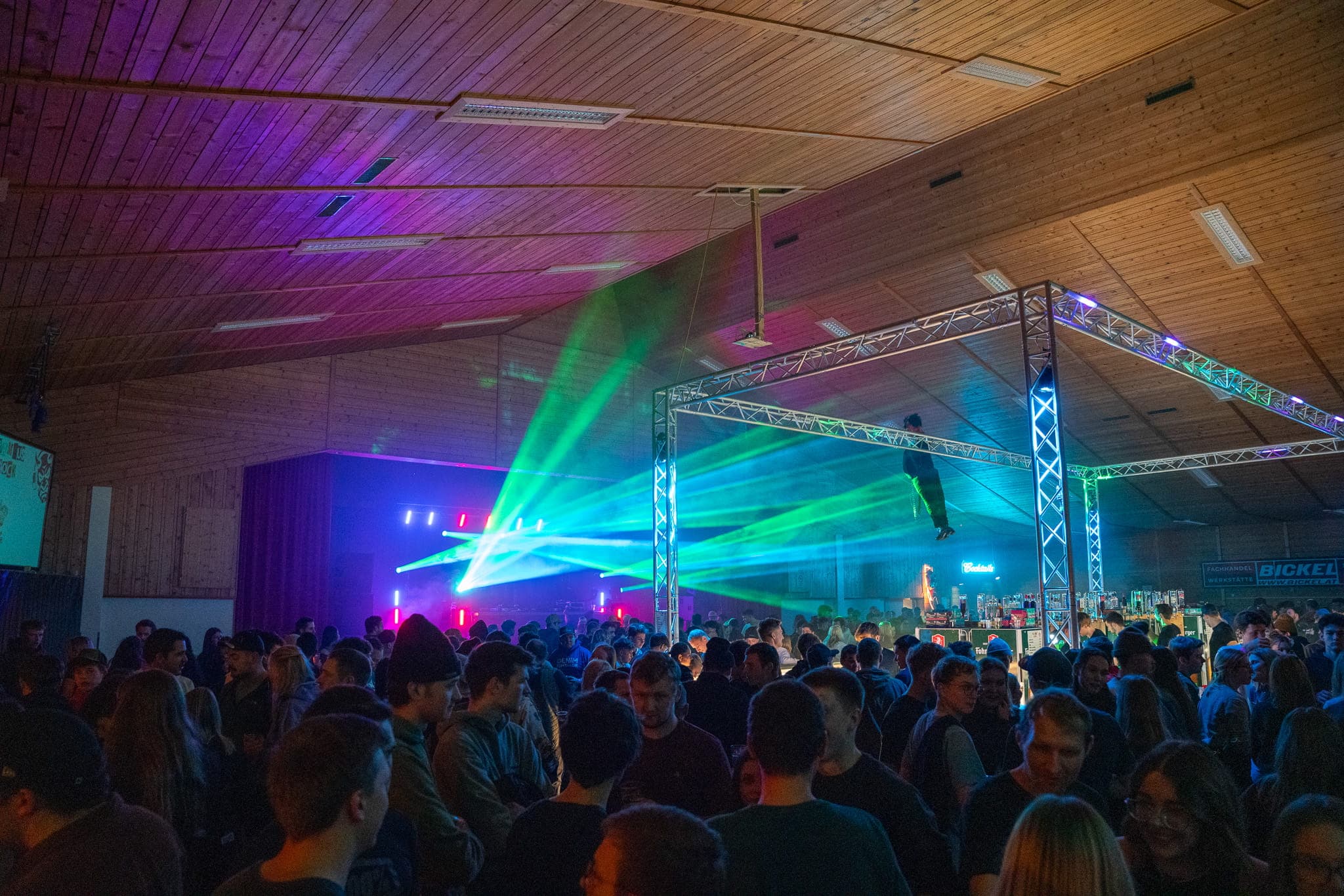Gäste vor der beleuchteten Bühne und der Bar
